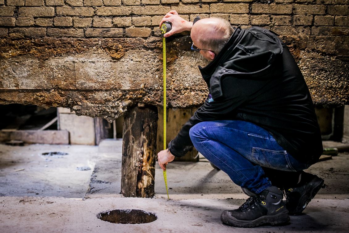 Person measuring the foundation of a house